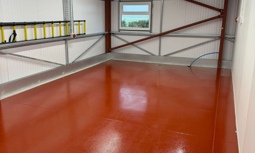 Glossy terracotta-red resin floor coating in a workshop with a seamless finish